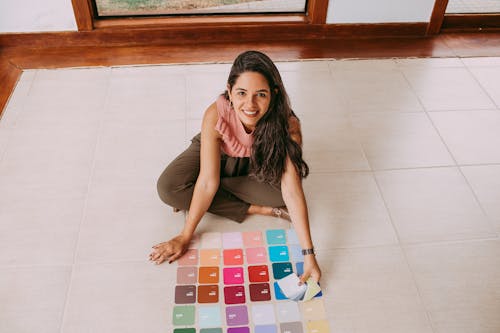 Smiling Woman Sitting on the Floor with Paint Samples 