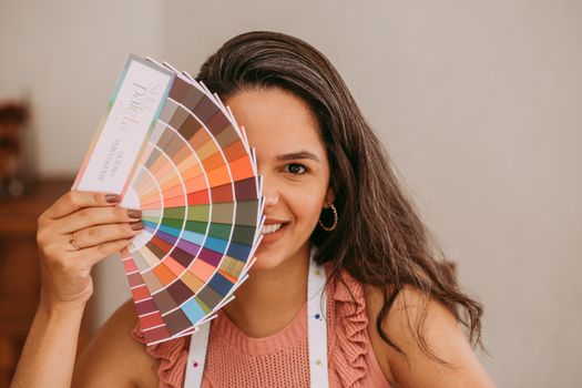 A smiling woman holds a color palette, perfect for creative and design themes.