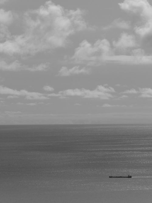 Free A black and white seascape featuring a solitary vessel under a cloudy sky. Stock Photo