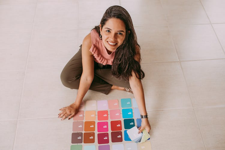 Brunette Woman Sitting On Floor With Colorful Fabric Samples