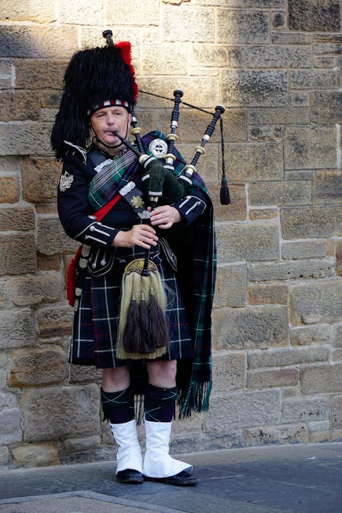 A Man in Traditional Clothing Playing Bagpipes