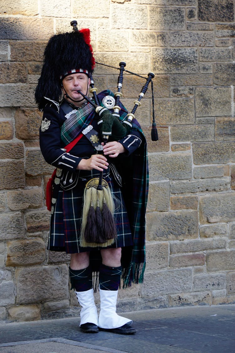 A Man In Traditional Clothing Playing Bagpipes