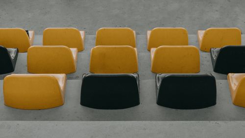 Free Empty yellow and black plastic seats in a stadium creating a pattern. Ideal for sports and architecture themes. Stock Photo