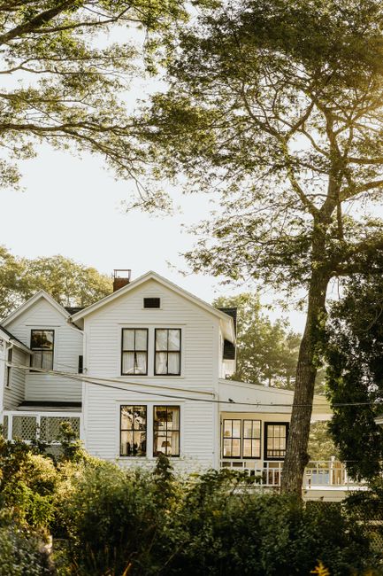 Secluded white house surrounded by lush greenery on a sunny day.