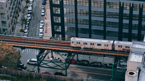 Free A drone captures a city train traveling on an elevated track amidst urban streets and buildings. Stock Photo