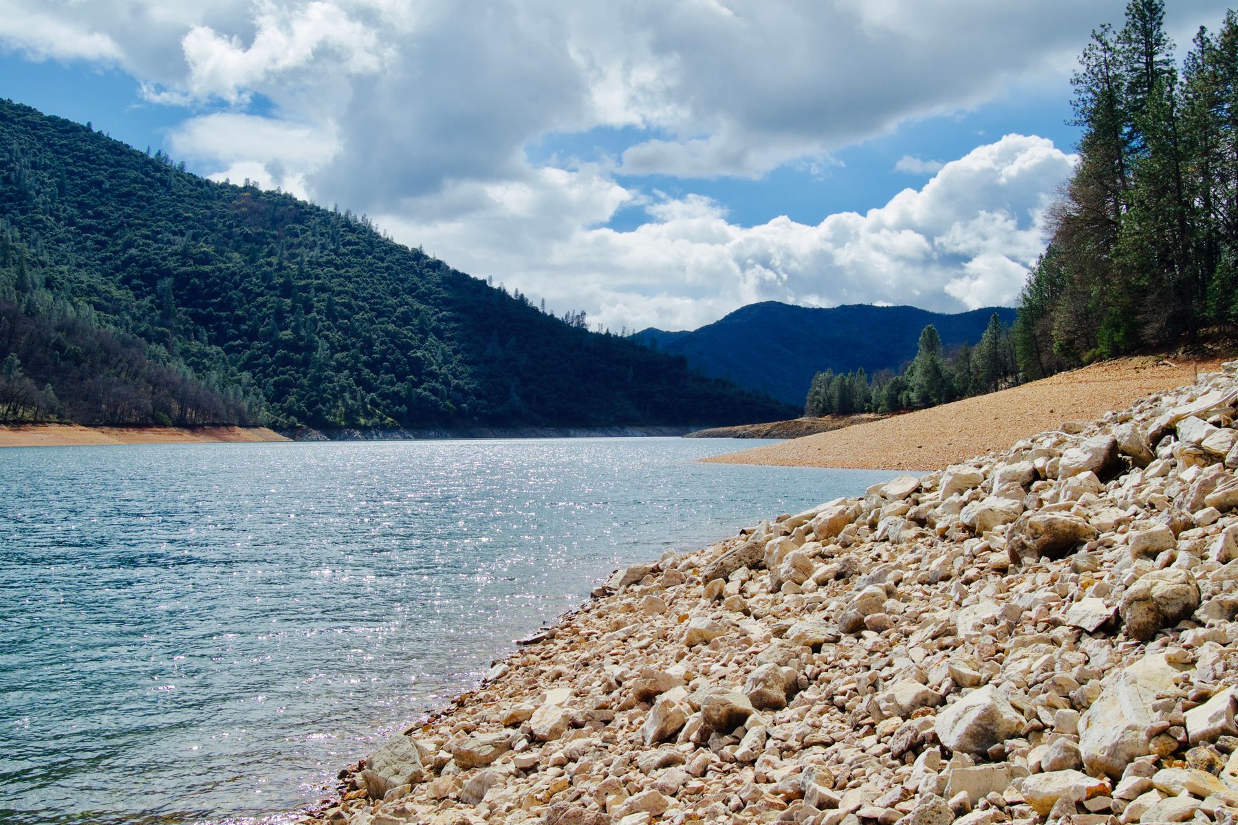 Lago azul con orilla de piedras en un día despejado