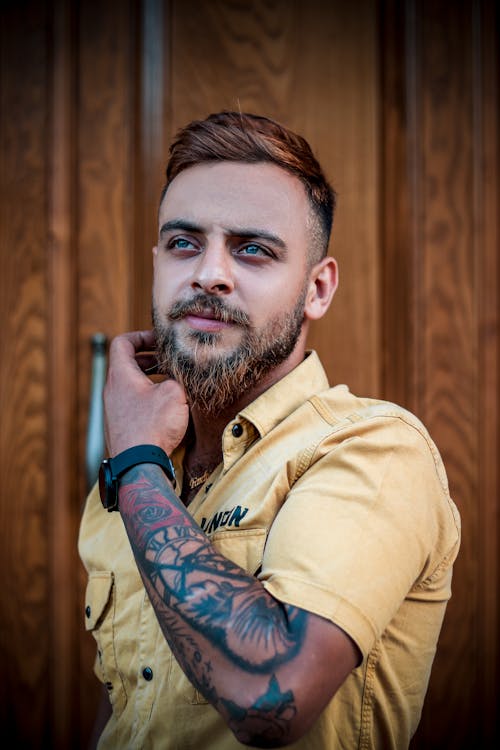 Portrait of Bearded Man in Yellow Shirt with Arm Tattoo