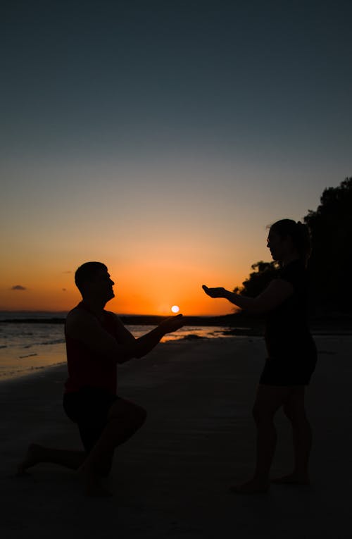 Man Giving Sun to Woman at Sunset 