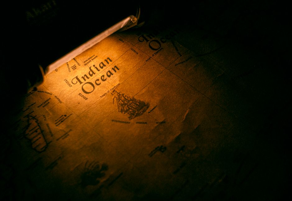 Close-up of a vintage map displaying the Indian Ocean under warm lighting, evoking a sense of exploration.