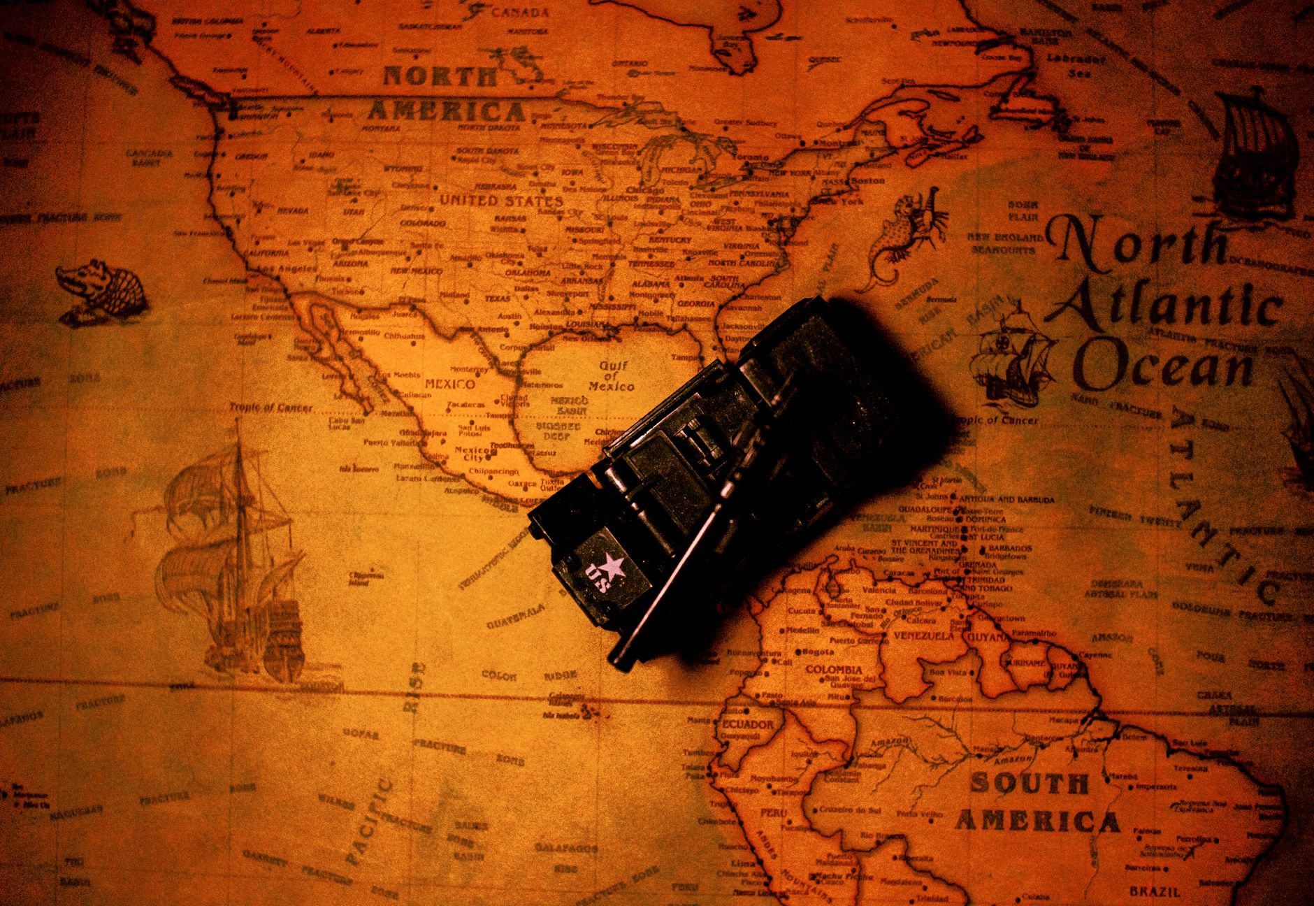 Artistic image of a vintage map showing North America with a toy tank on it. Rich tones and historical elements.