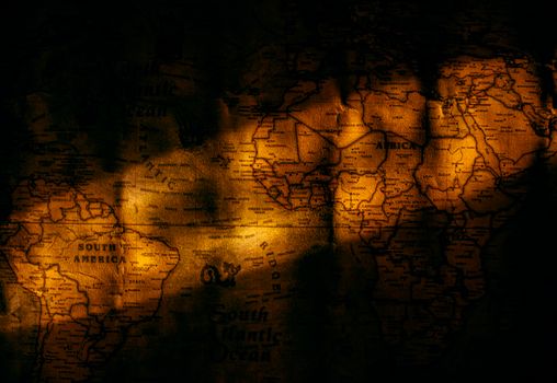 A vintage world map illuminated by dramatic light, creating a mysterious atmosphere.