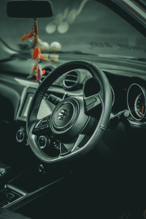 Free Close-up view of a Suzuki Swift's black car interior focusing on the steering wheel and dashboard. Stock Photo