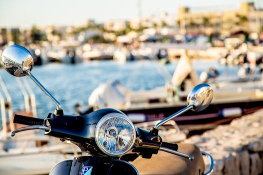 阳光明媚的海滨码头上，一辆经典滑板车的特写视图以船只作为背景