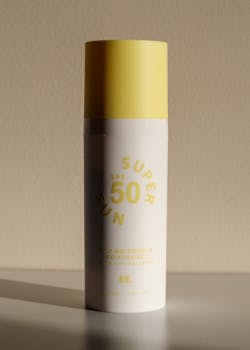 Close-up shot of SPF 50 sunscreen bottle with yellow cap in natural light.
