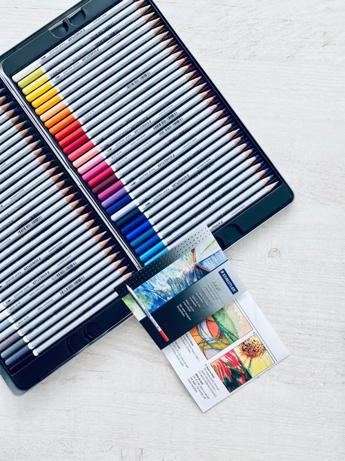 Free A flat lay of a colorful colored pencils set and guide on a wooden surface. Stock Photo