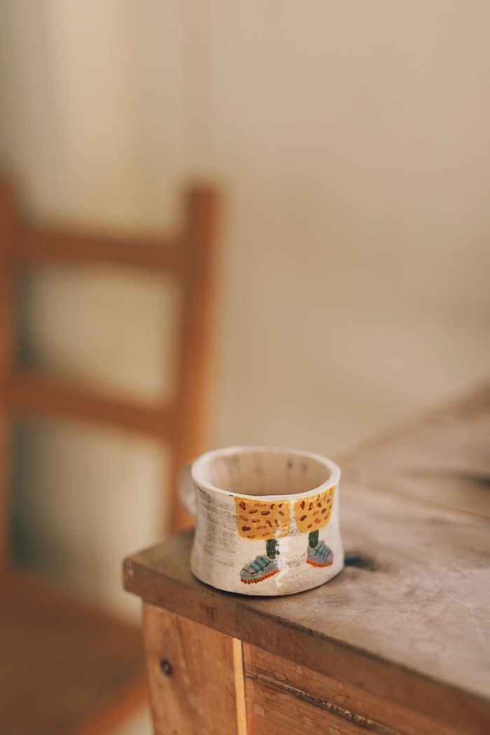 Small hand-painted stoneware mug on a wooden table, photo by Nida Kurt on Pexels