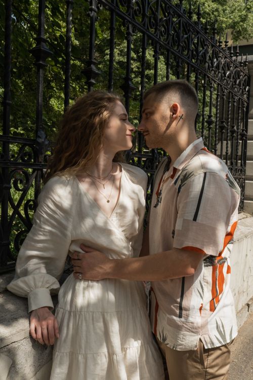 Free Close-up of a romantic couple embracing by a wrought iron fence outdoors. Stock Photo