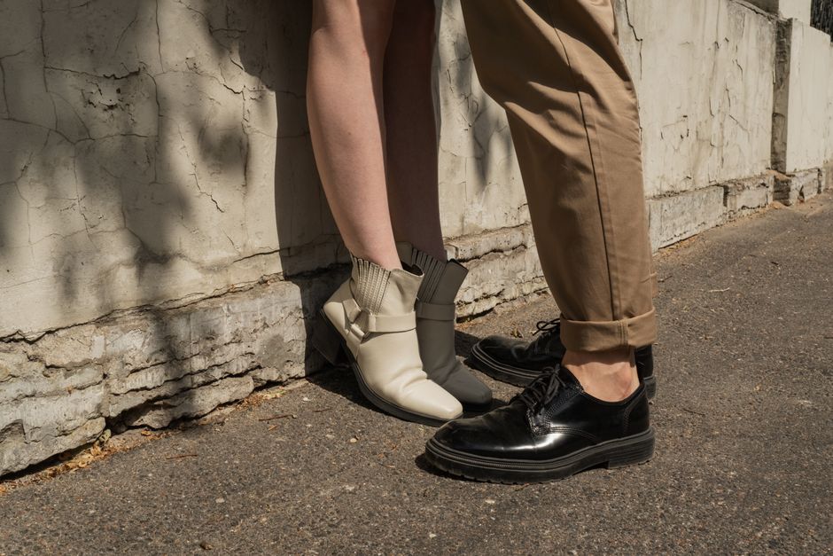 Close-up of a couple's feet in stylish shoes on an urban street, conveying fashion and casual interaction.