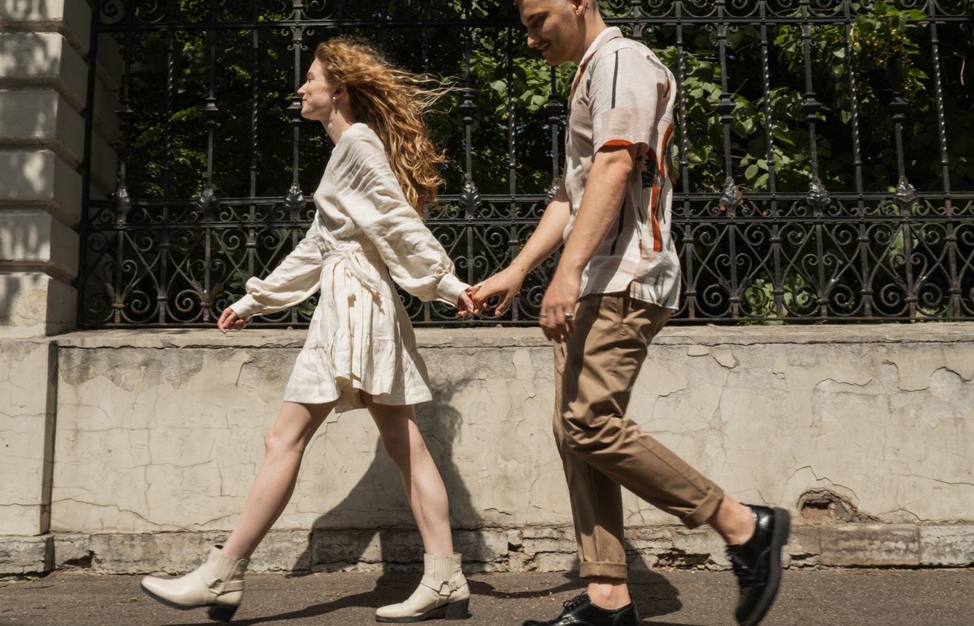 Young couple holding hands while walking on a sunny day, capturing a moment of togetherness.