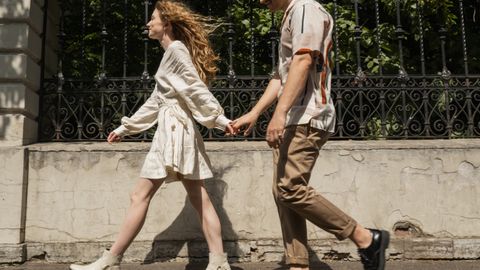 Young couple holding hands while walking on a sunny day, capturing a moment of togetherness.