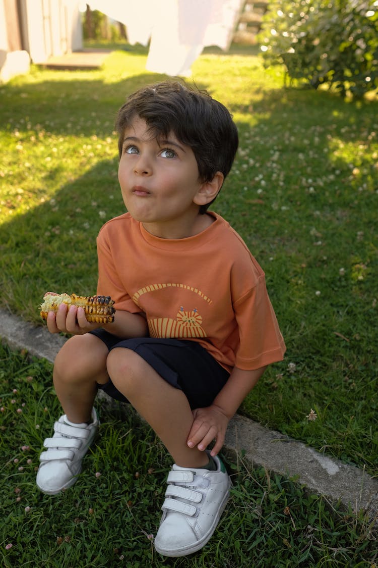 A Boy Eating Grilled Corn On The Cob