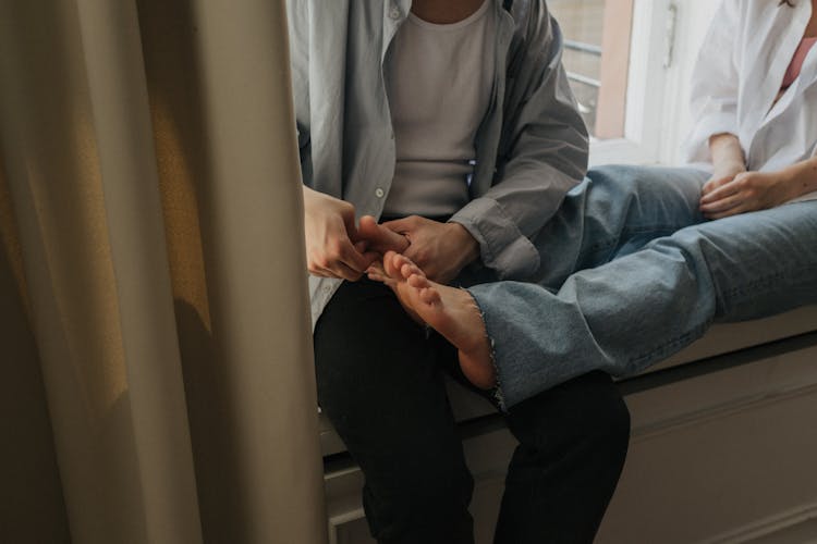 Man In Gray Shirt Massaging The Toes Of A Woman 