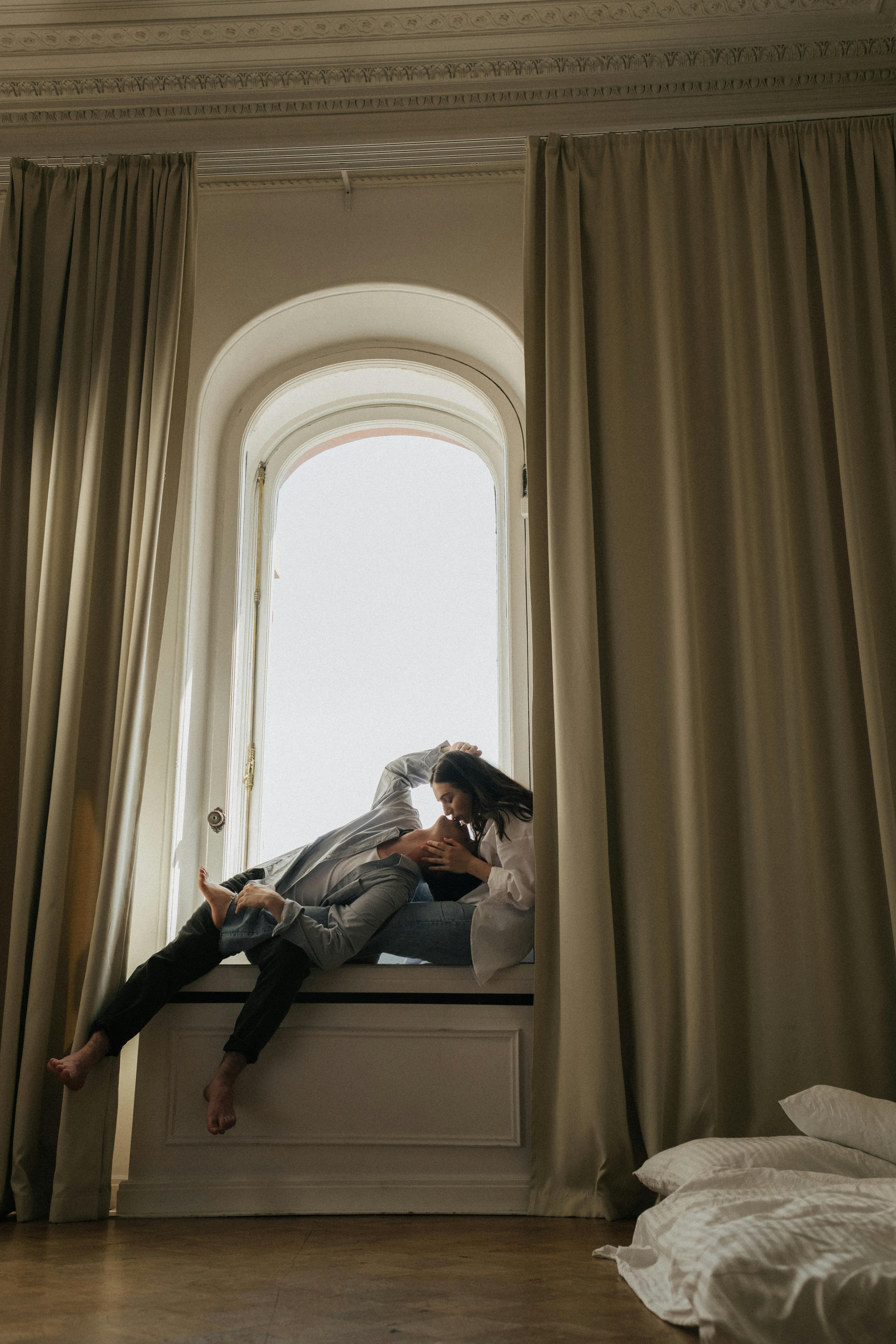 Free Man and Woman Sitting by the Window Kissing Stock Photo