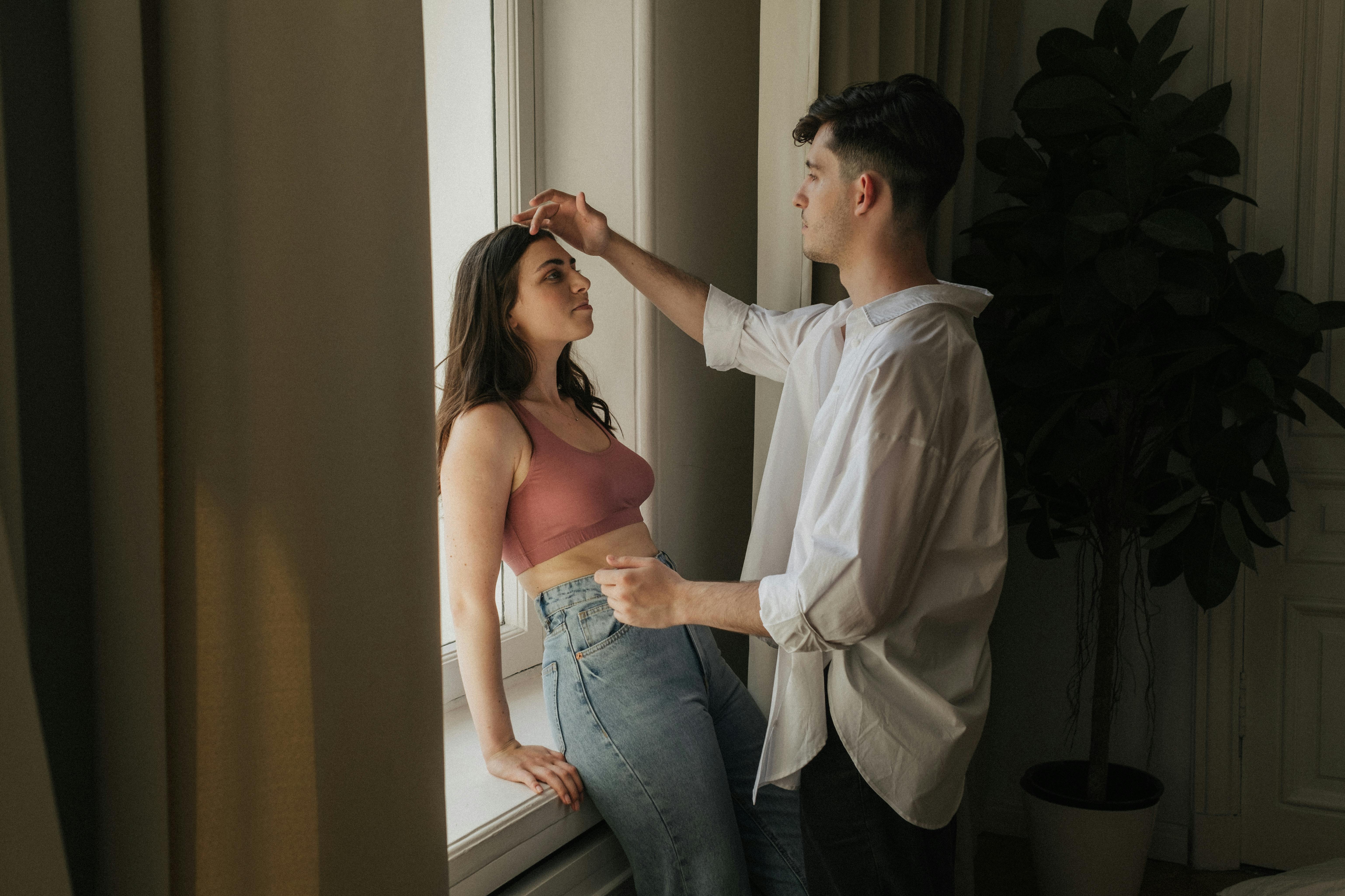 A romantic moment between a couple by the windowsill, capturing intimacy and warmth.