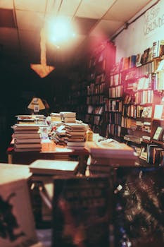 A dimly lit bookstore filled with stacks of books on tables, creating a cozy and inviting atmosphere.