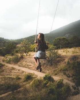 A woman enjoys swinging in a picturesque outdoor setting, embracing nature's beauty.