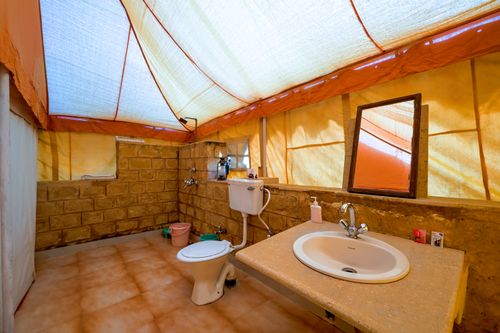Free A rustic tent bathroom setup with brick walls and essential amenities in Jaisalmer, India. Stock Photo