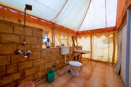 Free Rustic camping bathroom interior with stone walls and warm lighting in Jaisalmer, India. Stock Photo