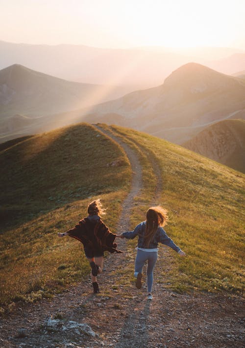 Free Women Running on the Mountain Trail During Sunset Stock Photo