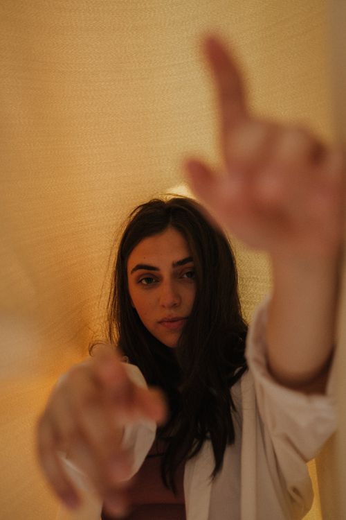 Free Portrait of a woman indoors, reaching towards the camera with a warm, soft lighting effect. Stock Photo
