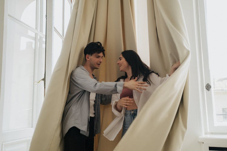 A Couple Standing Near The Curtain