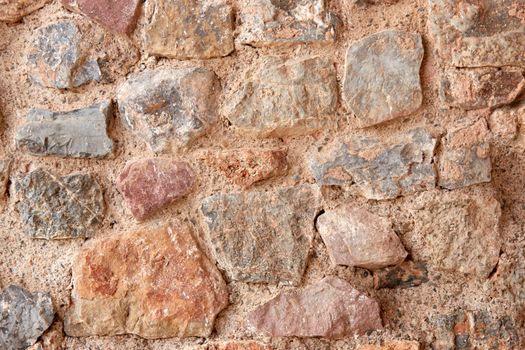 Close-up view of a rugged stone wall with rough textures.