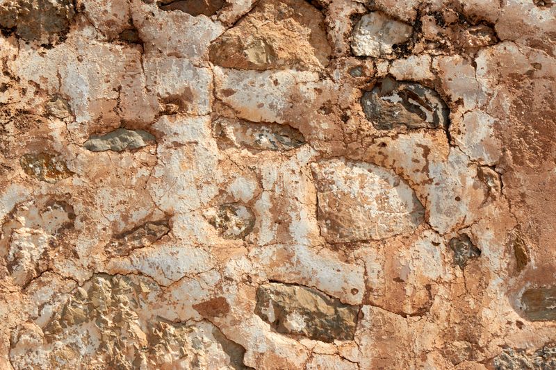 Close-up of a rustic stone wall with cracked, earthy textures, perfect for backgrounds.