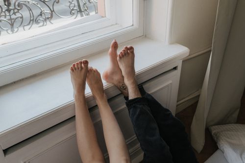 Free Two people relaxing with bare feet on a windowsill, enjoying a sunny indoor moment. Stock Photo