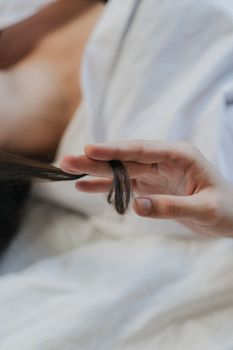 A delicate hand gently holds a lock of hair, showcasing an intimate and soft moment.