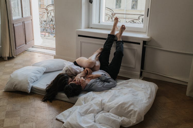 Photo Of Couple Lying On Bed While Kissing