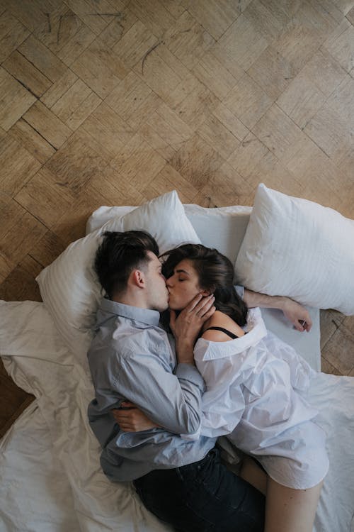 Free Young Couple Kissing While Lying at Bed  Stock Photo