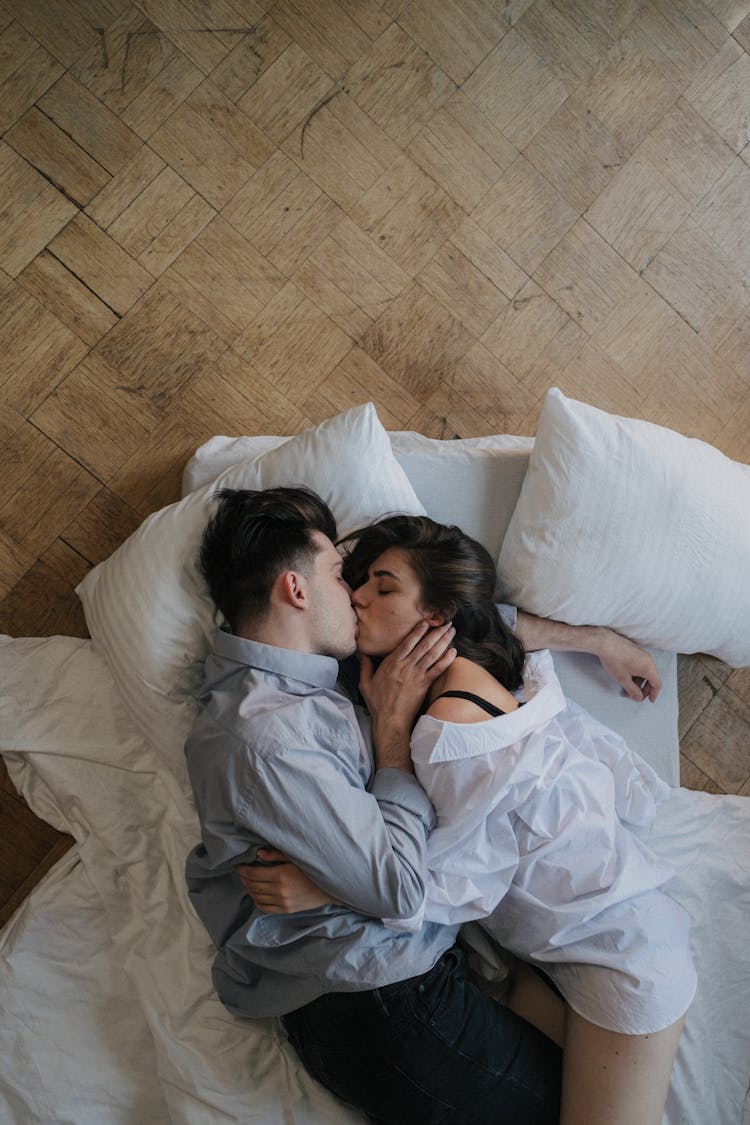 Young Couple Kissing While Lying At Bed 