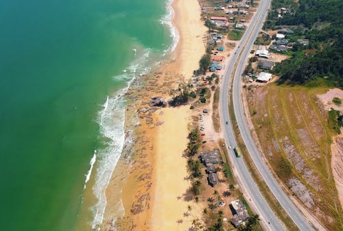 бесплатная Аэрофотосъемка коричневого песчаного пляжа возле дороги Стоковое фото