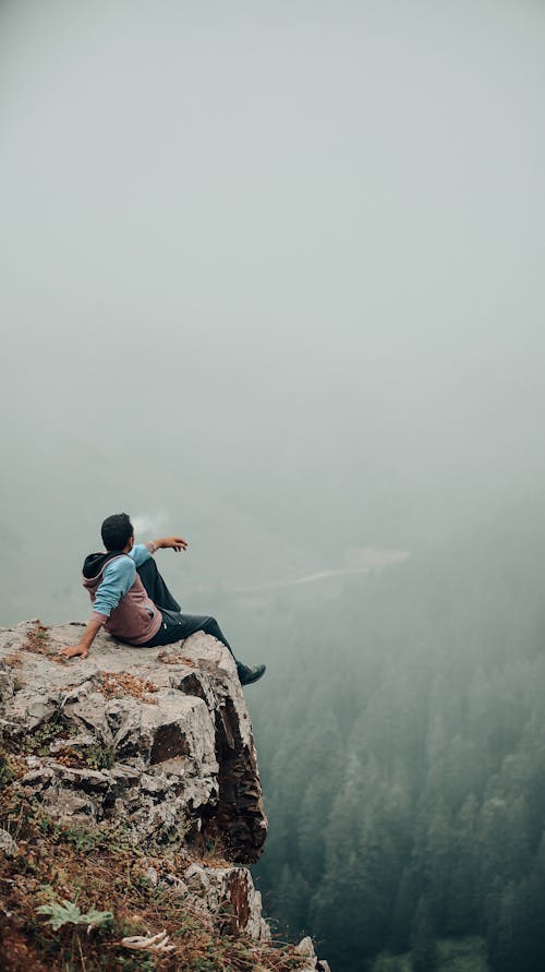 Free A Person Sitting at the Edge of a Cliff Stock Photo