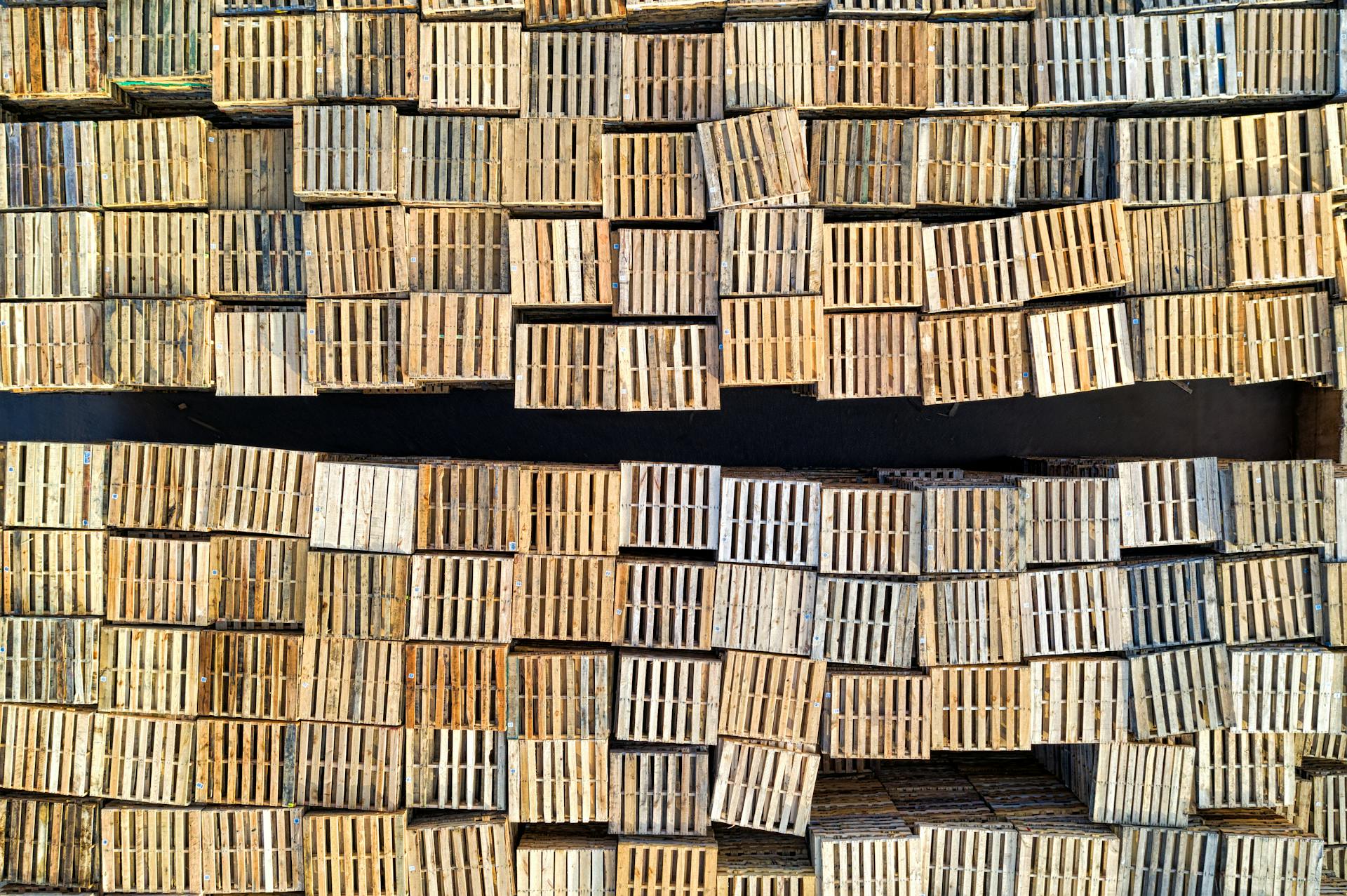 High angle shot of neatly stacked wooden pallets in an outdoor warehouse setting.