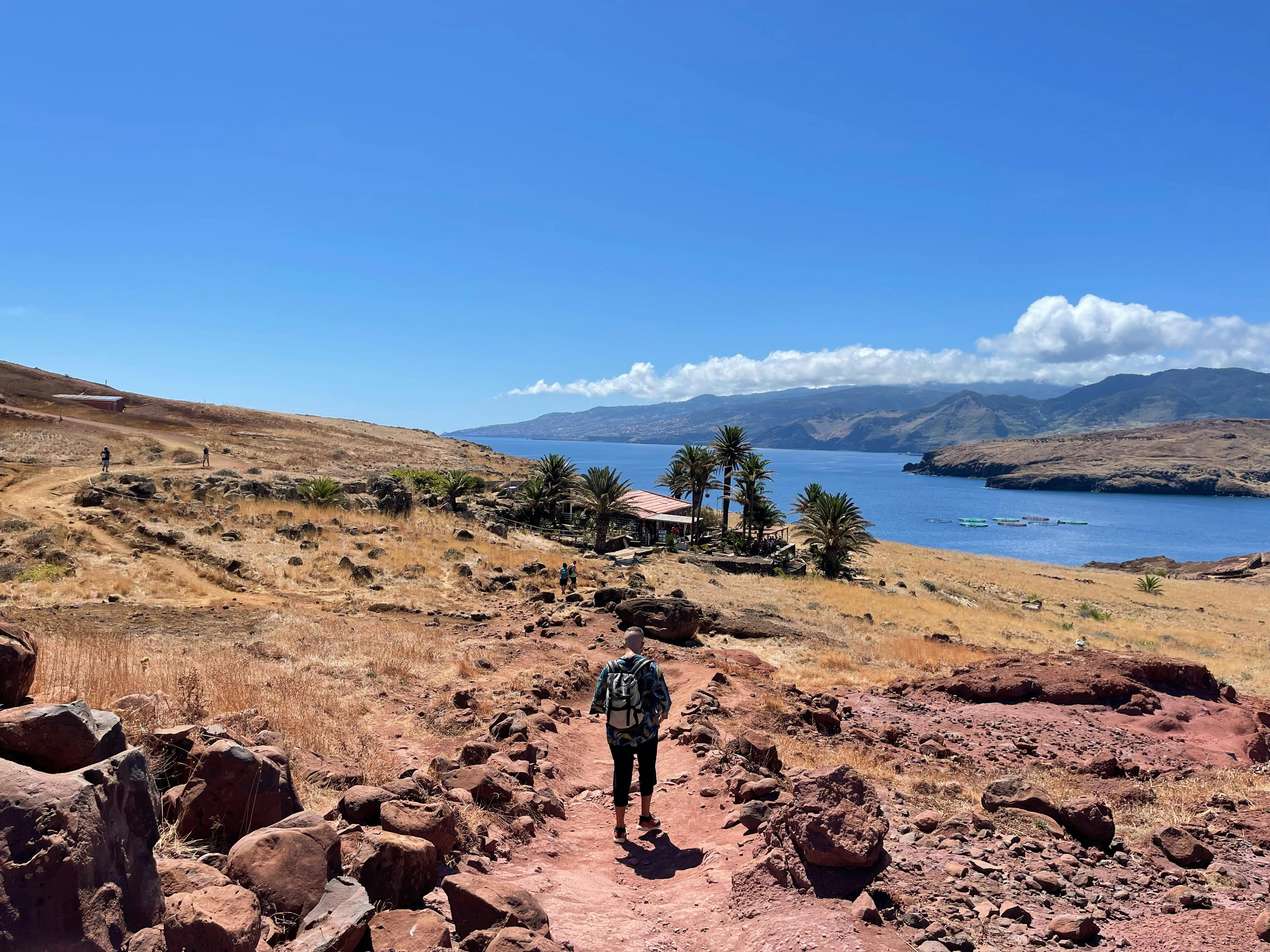 Hiker walking on Madeira coast trail with stunning ocean view under clear sky.