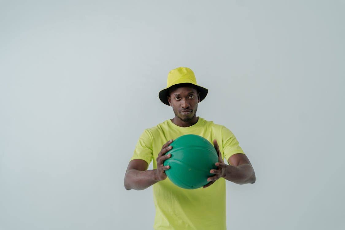 A Man in a Neon Bucket Hat Holding a Green Ball