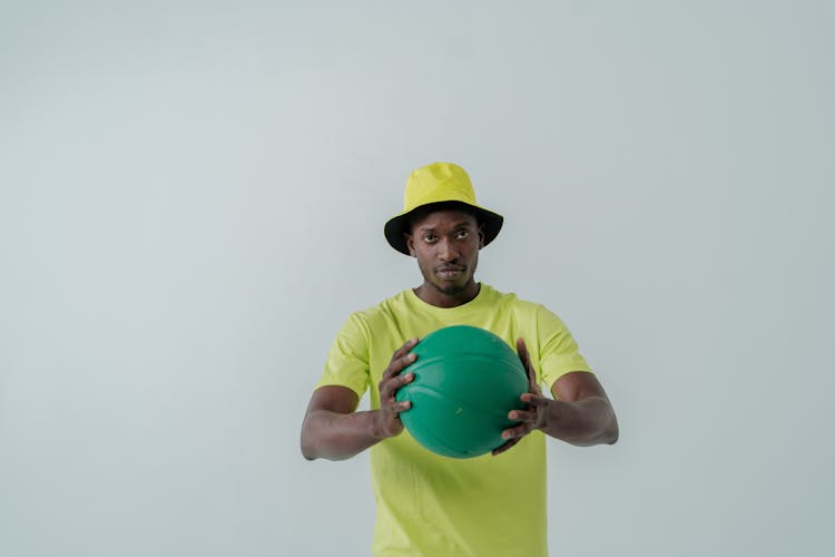 A Man In A Neon Bucket Hat Holding A Green Ball