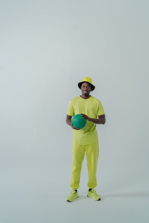 A Man Wearing a Neon Outfit Holding a Green Ball