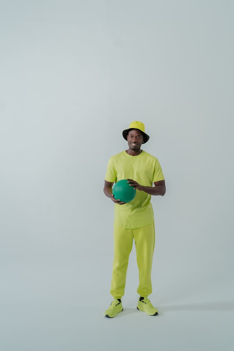 A Man Wearing A Neon Outfit Holding A Green Ball